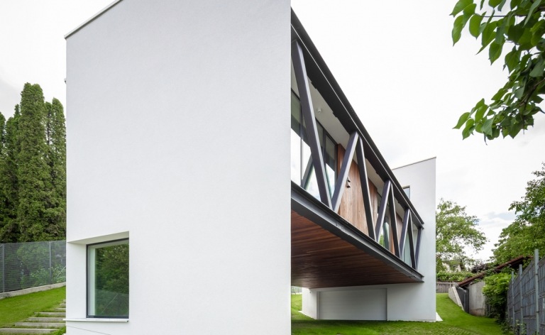 Haus in Hanglage mit verputzte weiße Fassade mit großen Fenstern und Holzelementen