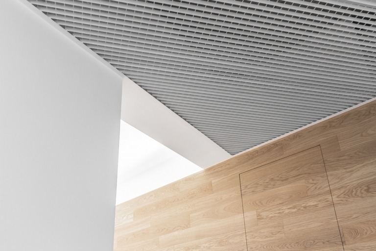 Holzboden und weiße Putzwände und Decke mit integriertem Lüftungssystem Beispiel für moderne Innenarchitektur