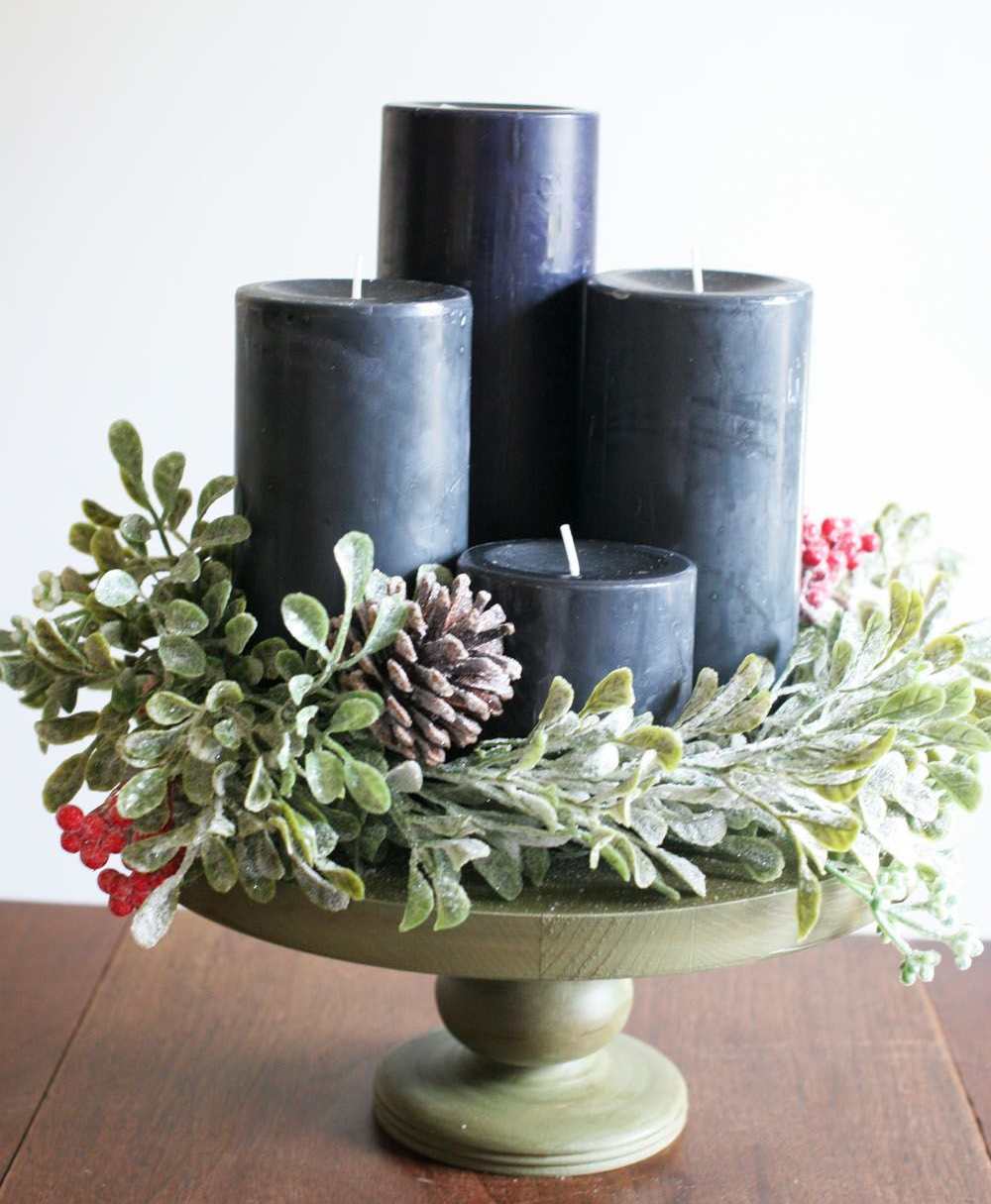 Weihnachtsgestecke aus Naturmaterialien dunkle Kerzen Tannenzapfen rote Schneeball Beeren immergrüne Salbei Zweige