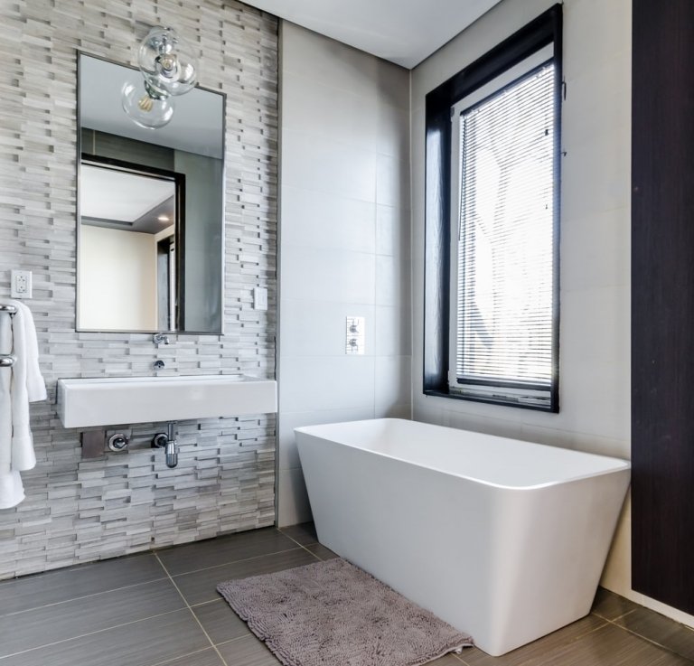 Moderne Bäder in Grau mit in Naturstein-verkleideten Wänden mit freistehender Badewanne ohne Unterschrank