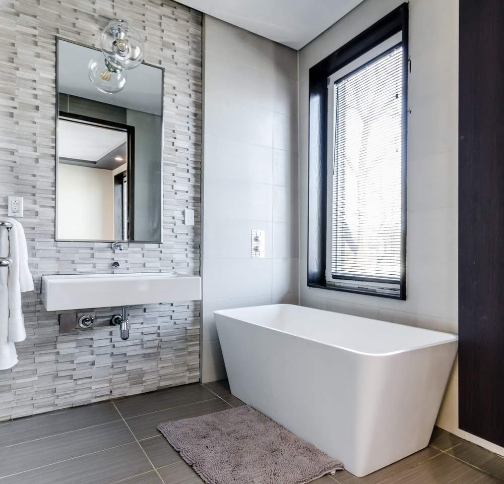 Modern baths in gray with natural stone-clad walls with freestanding bathtub without countertop