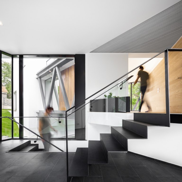 Modernes Einfamilienhaus mit Treppenhaus aus Schieferplatten und weißen verputzten Wänden und Glas-Geländern und bodengleichen Fenstern