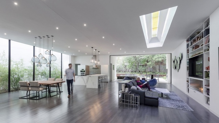 Modernes Einfamilienhaus nachhaltig bauen Dachfenster im Wohnbereich lassen mehr Sonnenlicht rein energiesparende Deckenleuchten am Abend