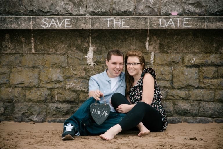 Verlobte posieren vor einer Mauer mit dem geplanten Heiratsdatum