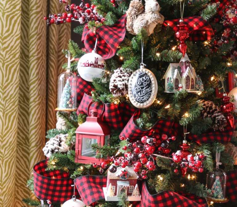 Weihnachtsbaum schmücken nostalgisch Dekoideen mit Laternen und Hagebutte und karierte Girlande aus Stoff und Tannenzapfen und Kunstschnee