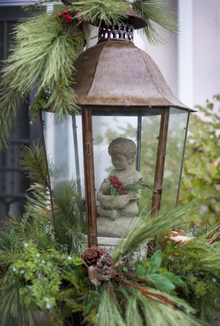 Winterdeko Garten Laterne weihnachtlich dekorieren mit Tannenzapfen und Engelfigur und Beeren und Tannengrün