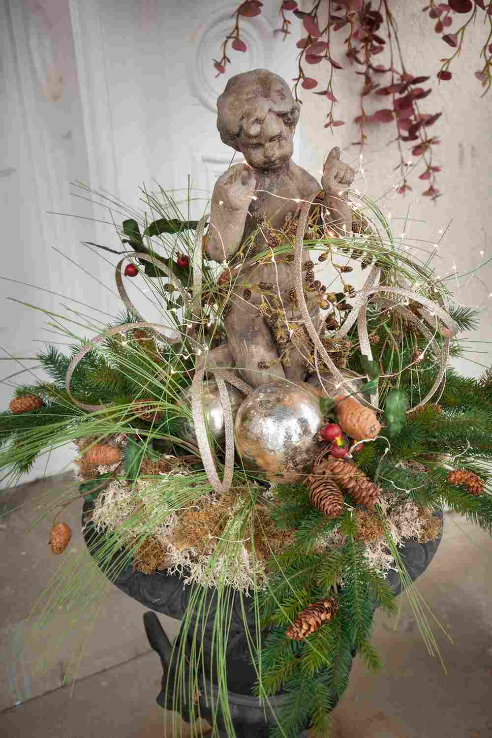 Winterdeko für Hauseingang selber machen Apmhora bepflanzen Engel Figur aus Stein und goldene Christbaumkugeln und Tannenzapfen und Stroh und Tannenzweige