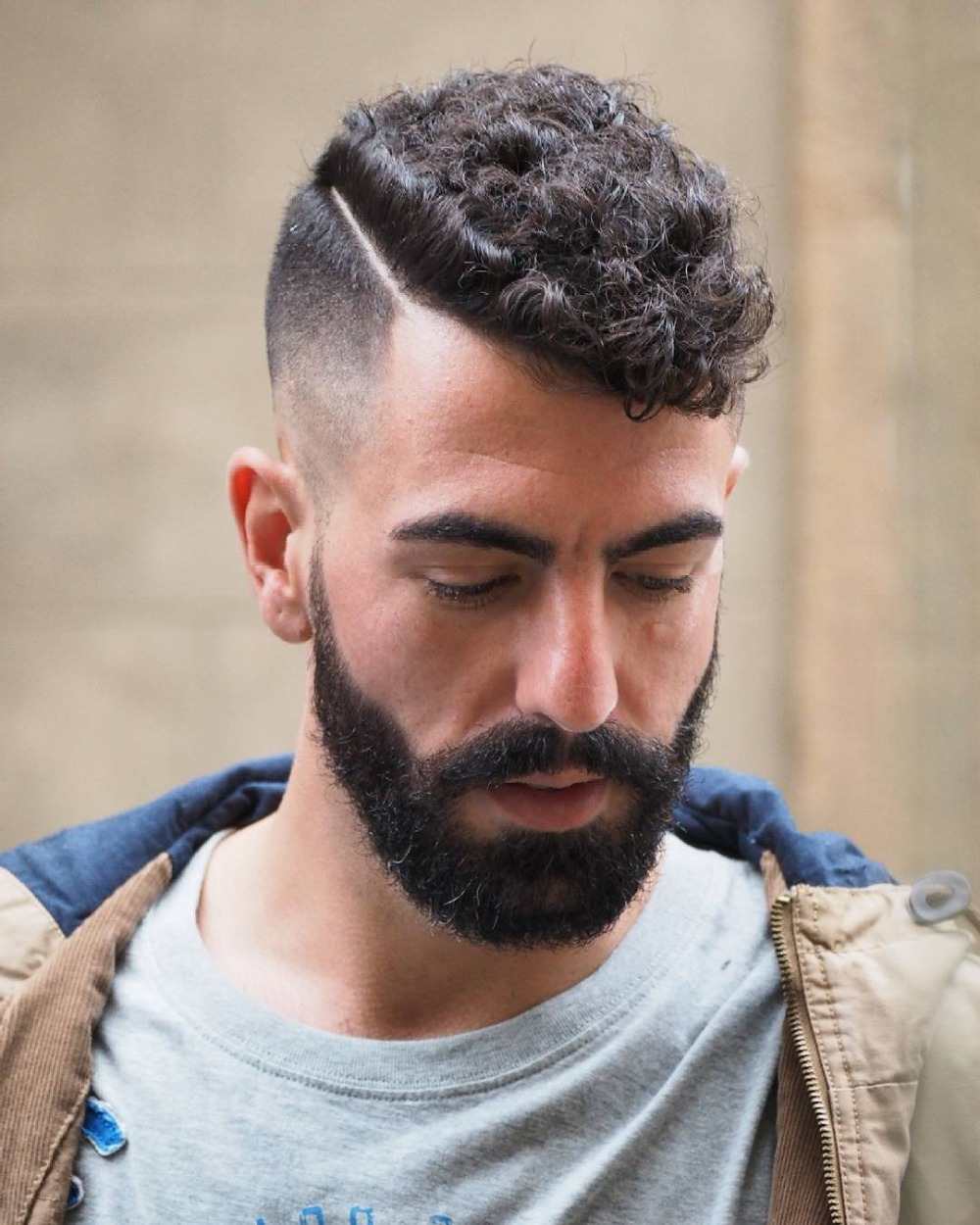 außergewöhnliche männerfrisur für lockiges haar mit kurz geschnittener kopfseite