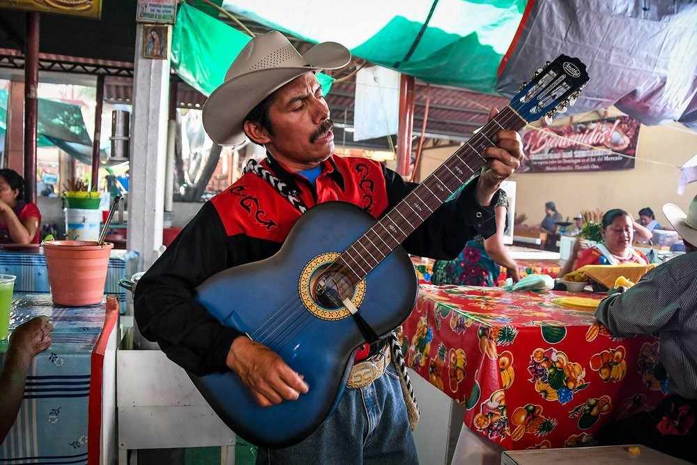 mexikanischer sänger mit gitarre spielt musik in restaurant