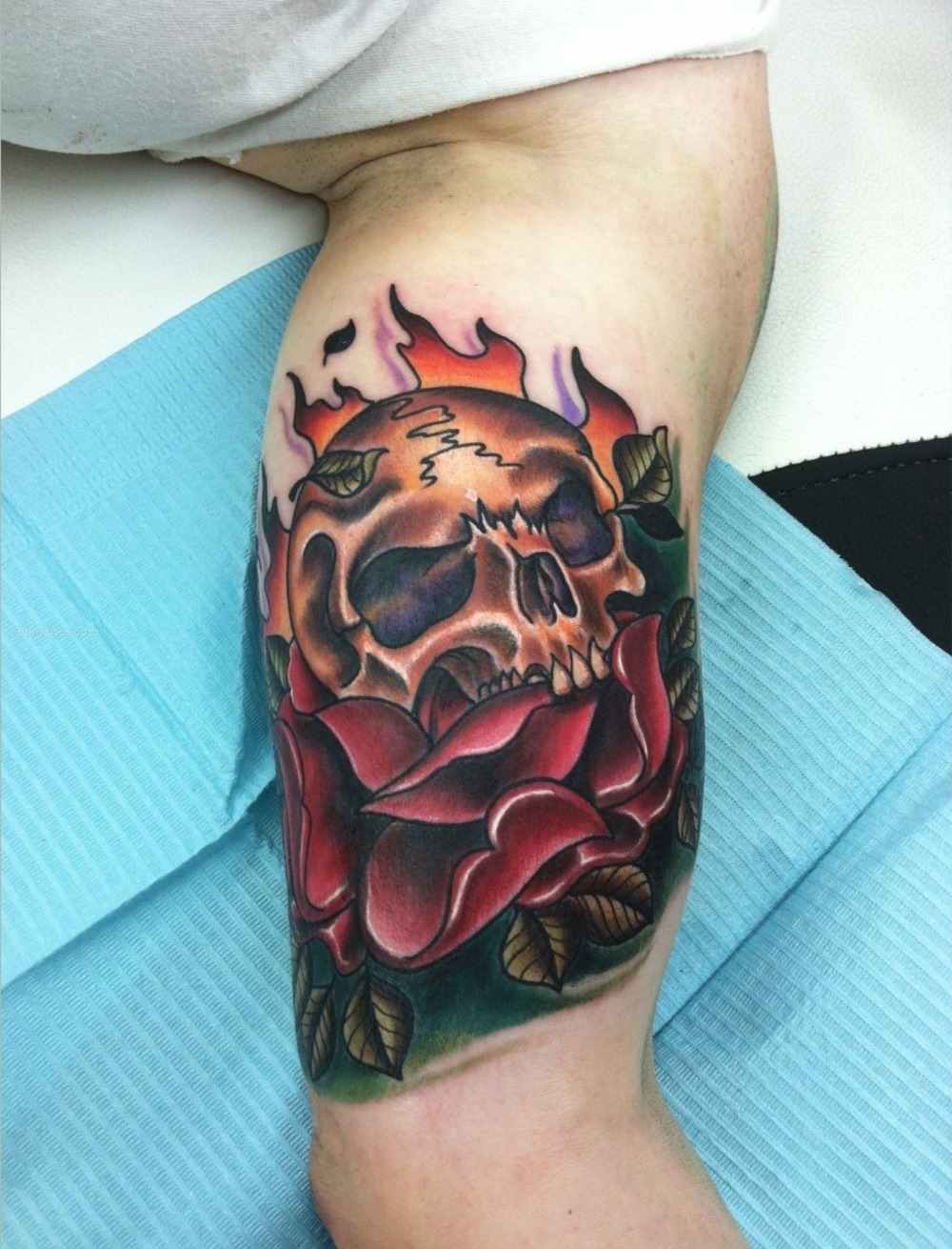 rockiges tattoo für herren mit schädel in flammen und rosen farbig