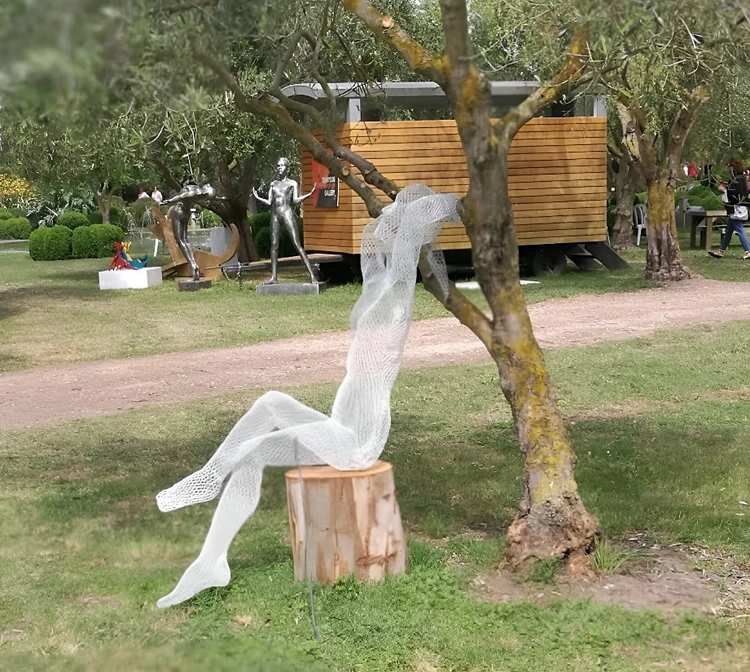 Sitzende Geisterfigur vor einem Baum im Garten