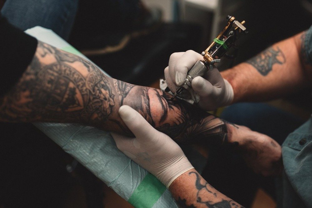 tattoo künstler mit maschine tätowiert den arm von mann im tattoo studio