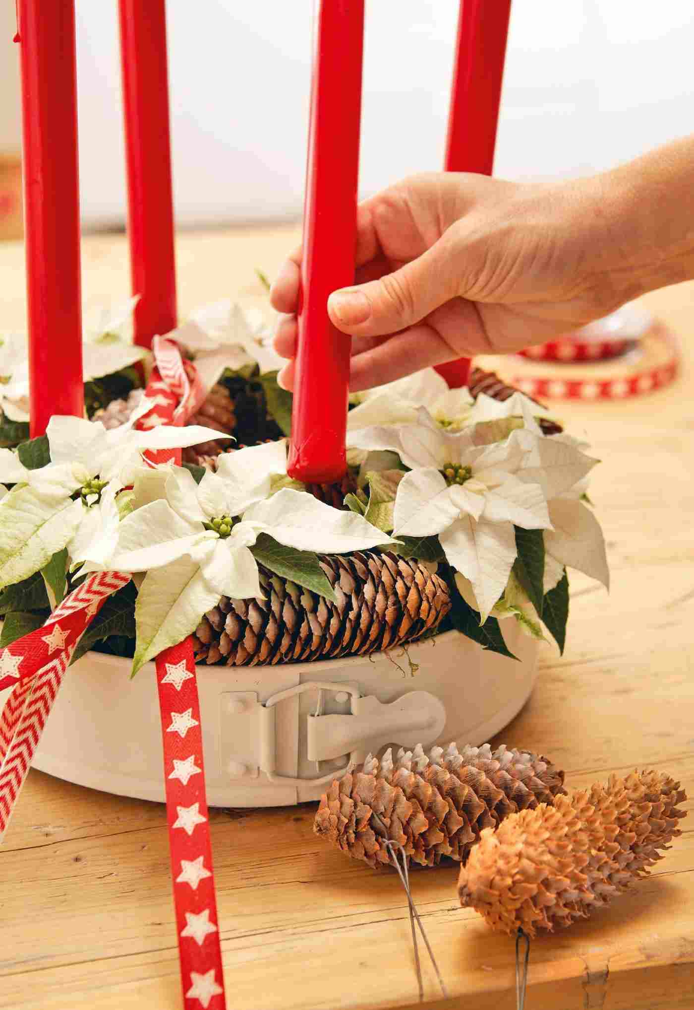 Idee für den Adventskranz mit weißen Weihnachtssternen und roten Kerzen