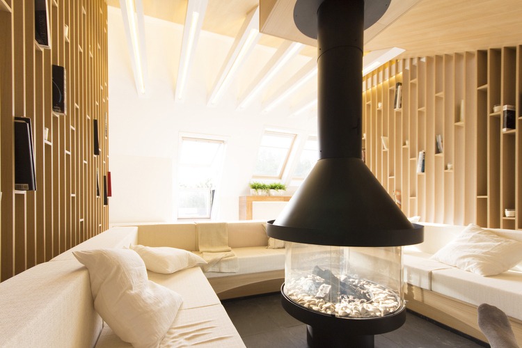 Raumteiler Regal im Dachgeschoss Kamin mit Holz Natursteinfliesen und weiße Decke