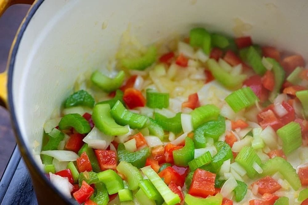 frische gemüse wie sellerie paprika und zwiebel im topf als zutaten für schnelle suppe