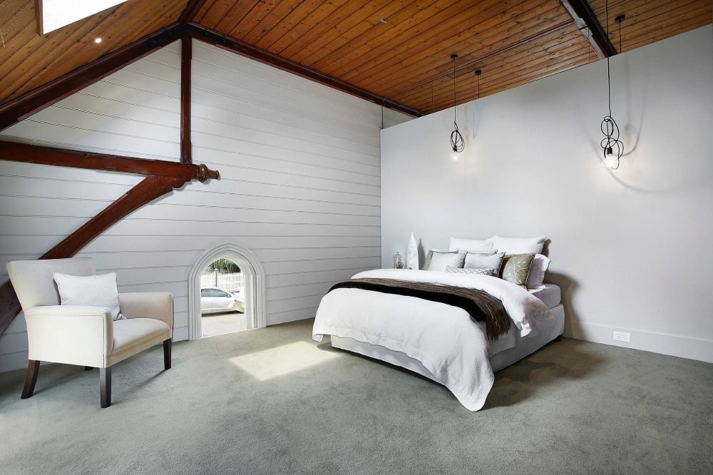 holzdecke und teppichboden schlafzimmer mit sessel und doppelbett hängeleuchte und weiße wände