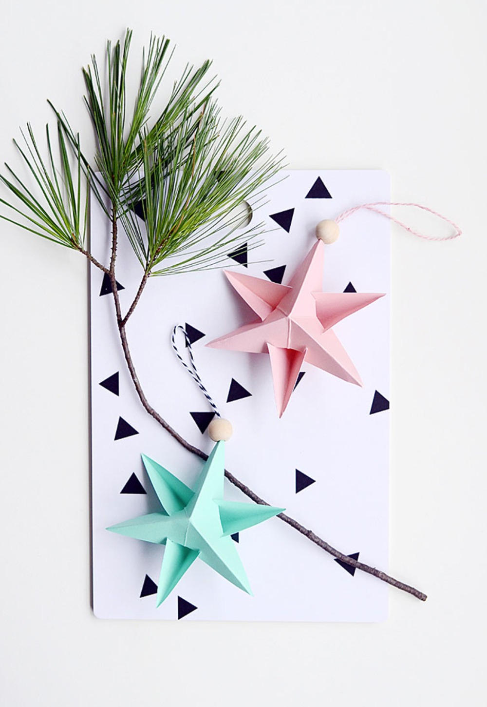 tannenzweig mit zwei sternen aus papier in rosa und minzgrün als dekoration weihnachten