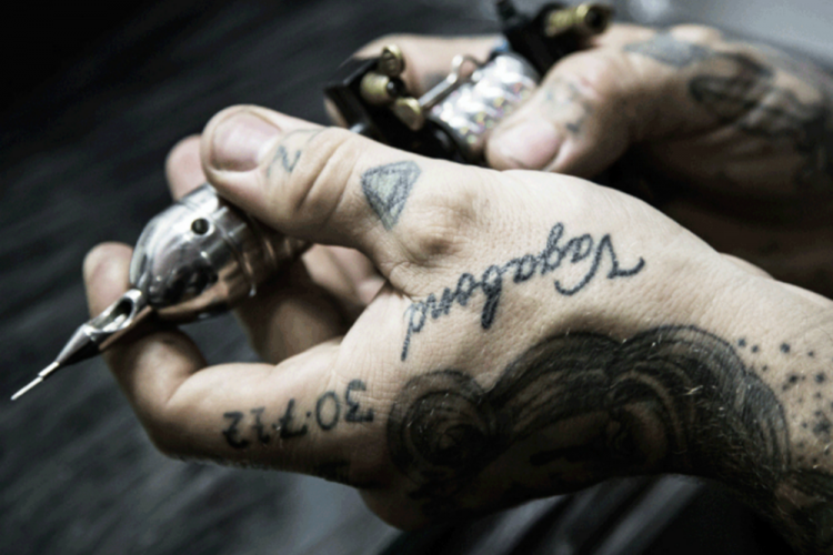 tätowiermaschine in händen mit botschaft tattoos