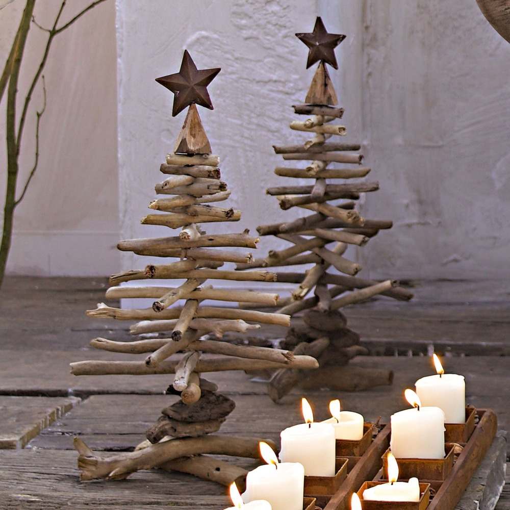 kleine diy tannenbäume aus treibholz mit weihnachtssternen im rustikalen look neben brennenden kerzen