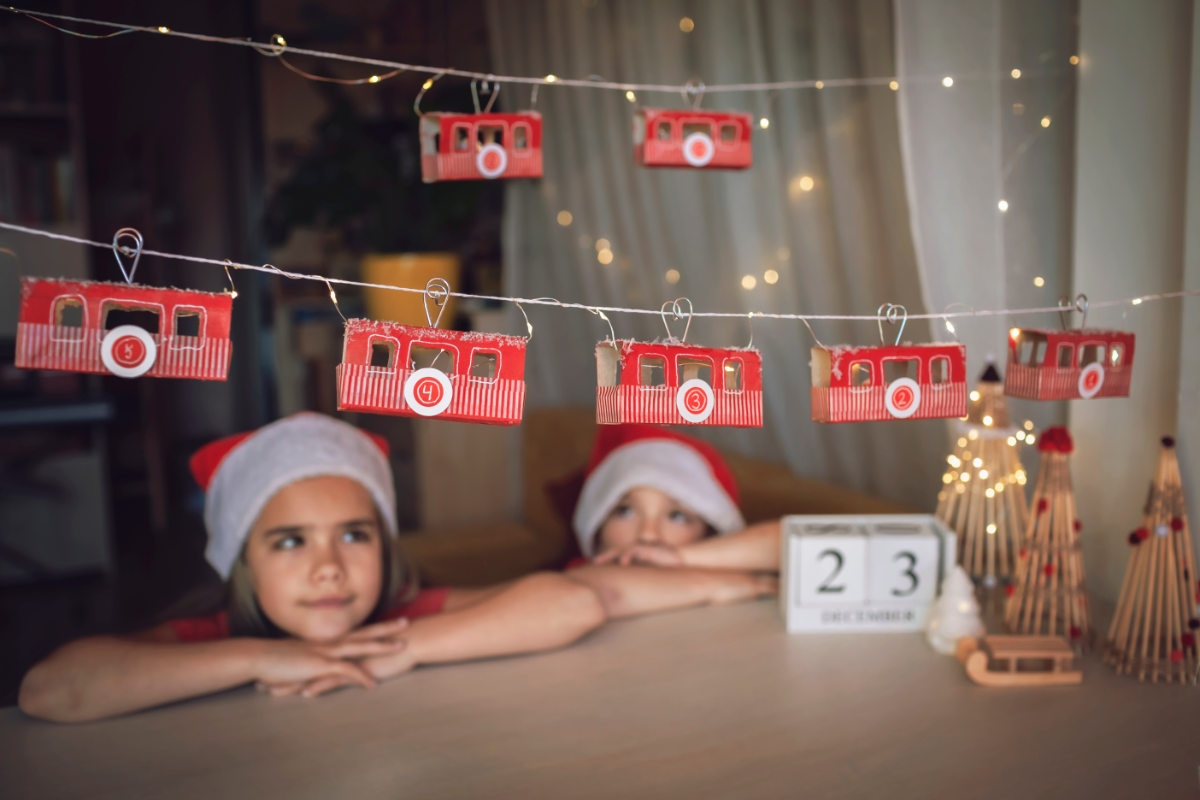 zwei kleine kinder mit einem selbstgemachten adventskalender in form eines zuges