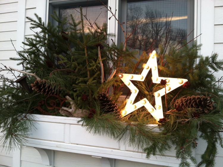 Fensterbank aussen weihnachtlich dekorieren Stern mit Lichter und langen Tannenzapfen und Tannenzweigen und Treibholz