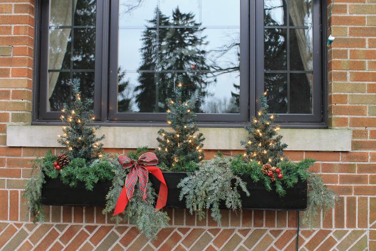 Fensterbank aussen weihnachtlich dekorieren mit Lichterkette und Mini Tannenbaum und roter Karoschleife