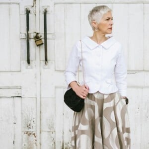 Fashionable Senior Woman Standing In Front Of The White Door