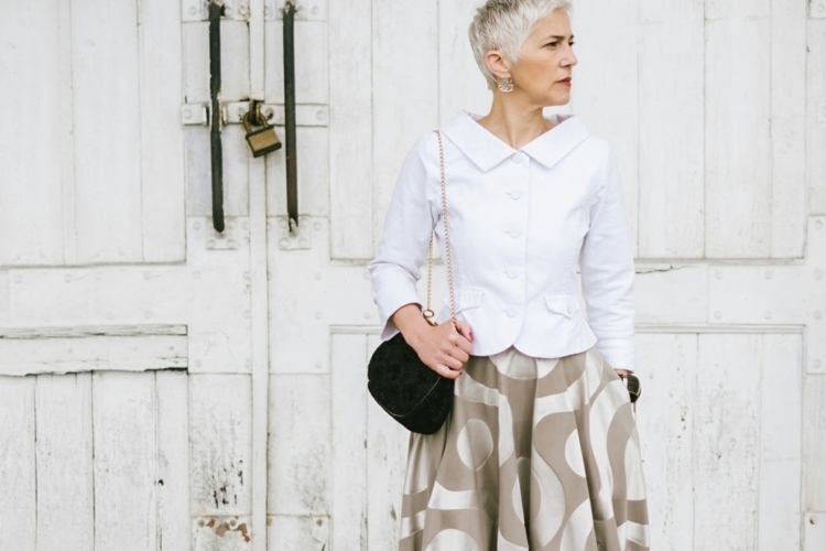 Fashionable Senior Woman Standing In Front Of The White Door