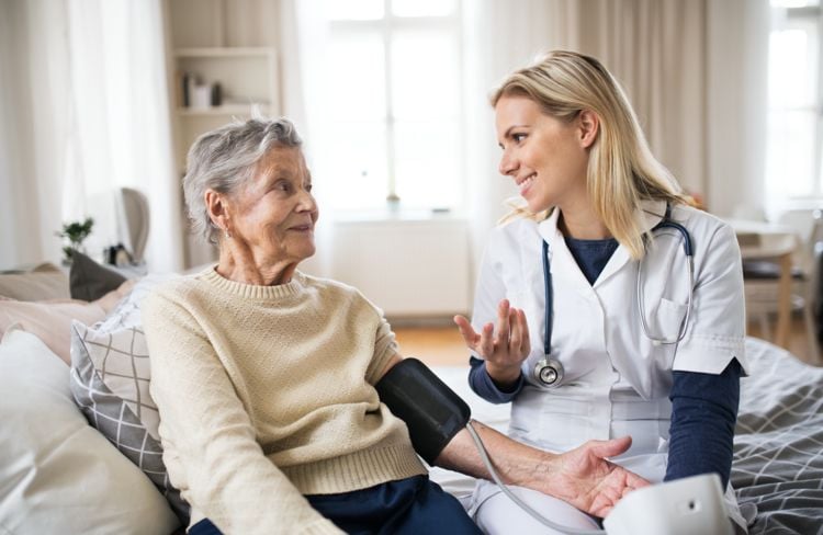 Pflegefachfrau spricht mit Frau bei Blutdruckmessung