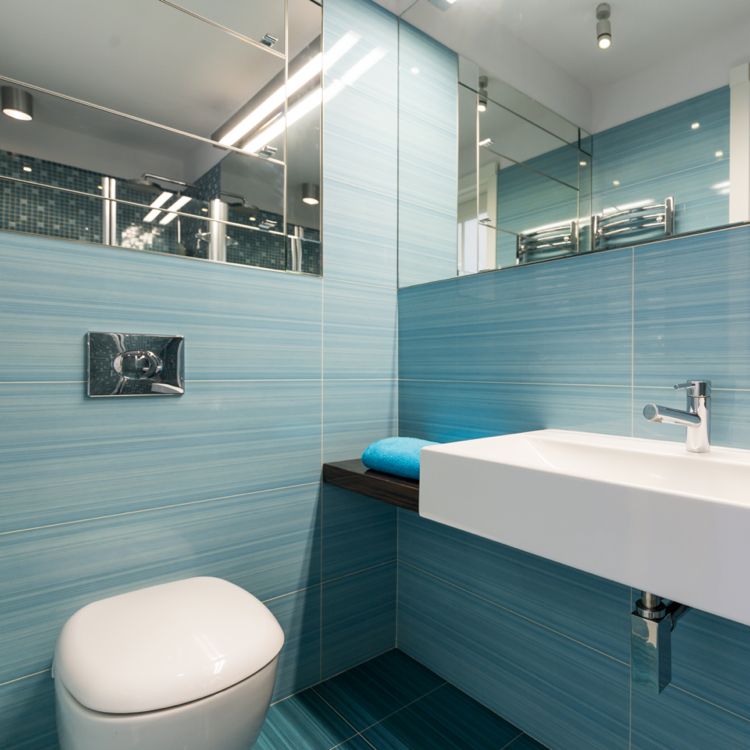 kleines Bad mit hellblauen Fliesen viele Spiegel reflecktieren das Licht und machen den Raum optisch größer