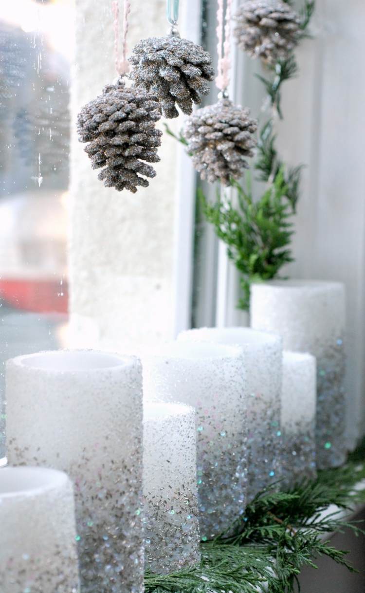 Fensterdeko im Januar mit glitzernden Kerzen und hängenden Tannenzapfen