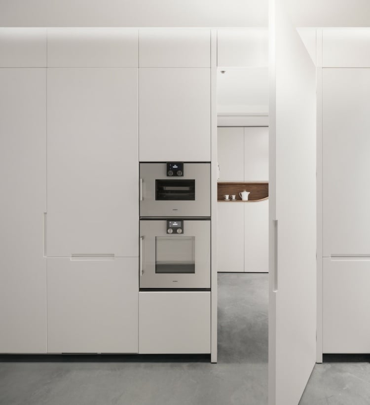 Minimalistische Küche in Weiß mit hohem Ofen und Einbauschränken