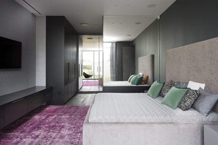 Schlafzimmer mit Wänden in Schiefergrau und Teppich in Pink und grüne Dekokissen am Bett