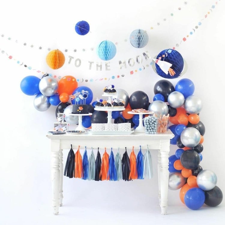 Weltraum Party in den Farben Orange, Blau und Silber mit Deko aus Quasten und Luftballons