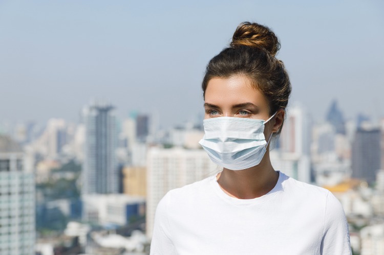 frau trägt eine gesichtsmaske wegen verschmutzter luft in der stadt