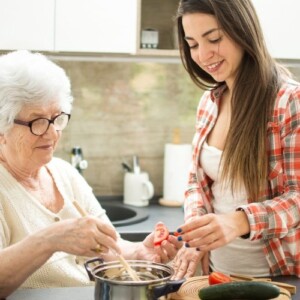 junge frau hilft alter dame mit alzheimer die zutaten beim kochen zu erkennen