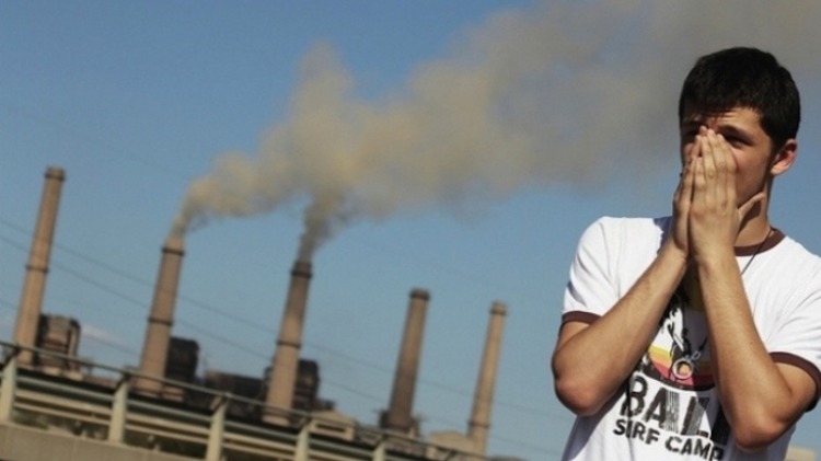 junger mann deckt seine nase wegen luftverschmutzung aus einer fabrik