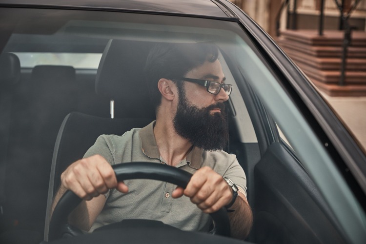 modern aussehender mann mit vollbart und brille im auto