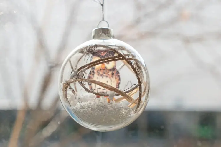 Schöne Hängedeko mit einer durchsichtigen Christbaumkugel und Kunstschnee