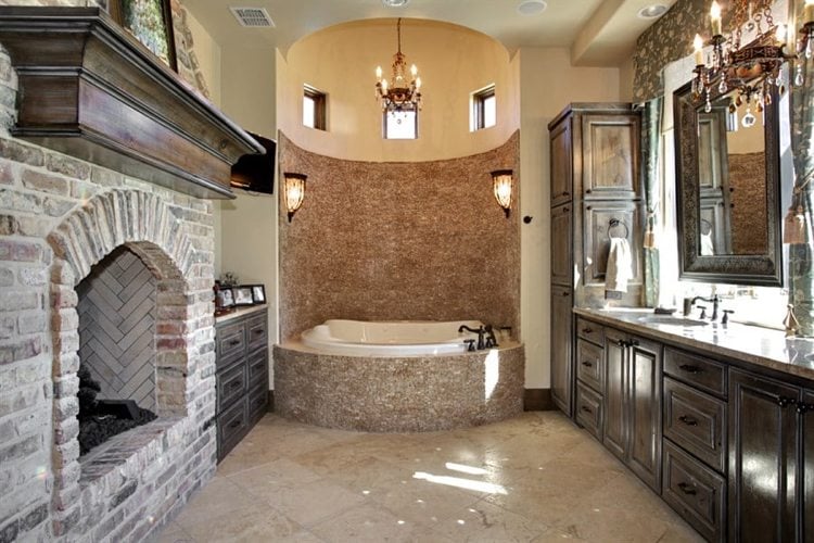 Spanish-style bathroom with a round bathtub with natural stone paneling and a fireplace