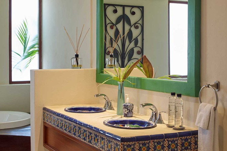 Modern Spanish-style bathroom with mosaic tiles and colorful sinks