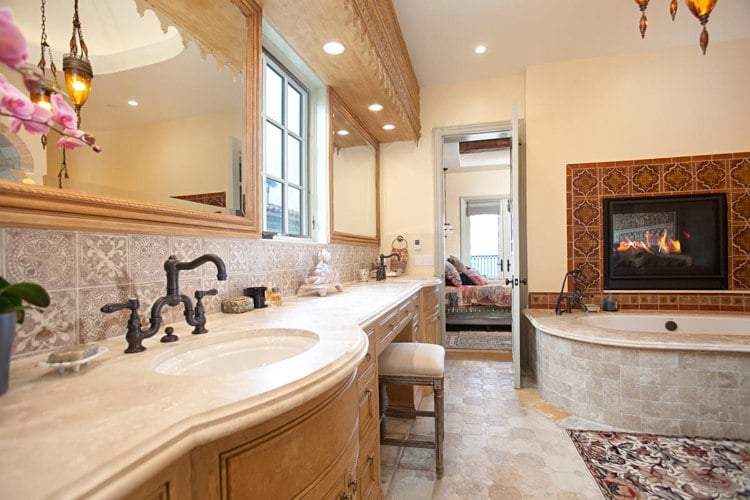 Bathroom with wood-burning fireplace and brass bathroom fittings and natural stone vanity