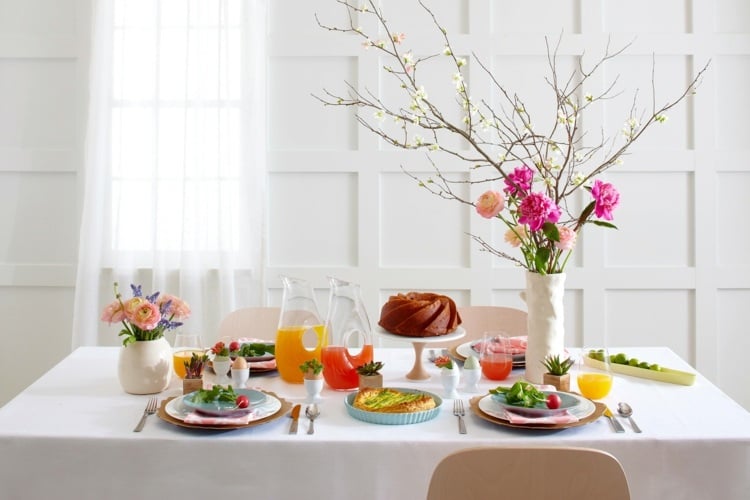 Frühstückstisch zu Ostern dekorieren mit Zweigen und pinken Blumen