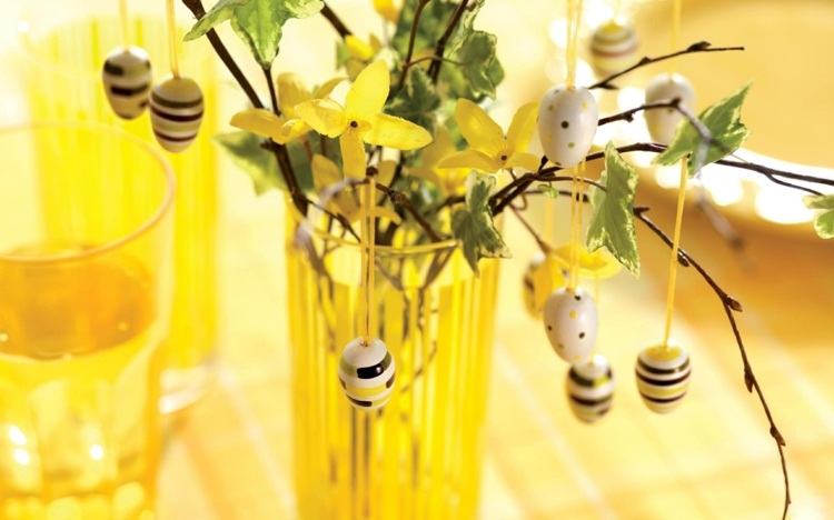 Gelber Osterstrauch mit kleinen Ostereiern aus Holz und gelben Blüten