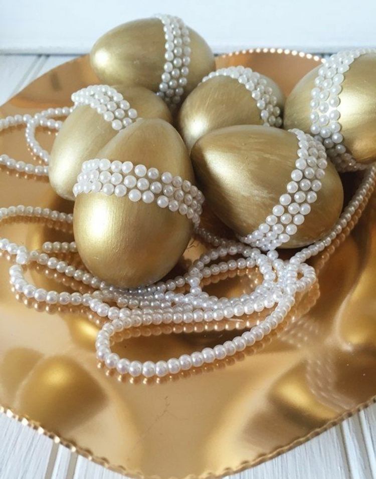 Goldene Eier mit weißen Perlen auf dem Ostertisch