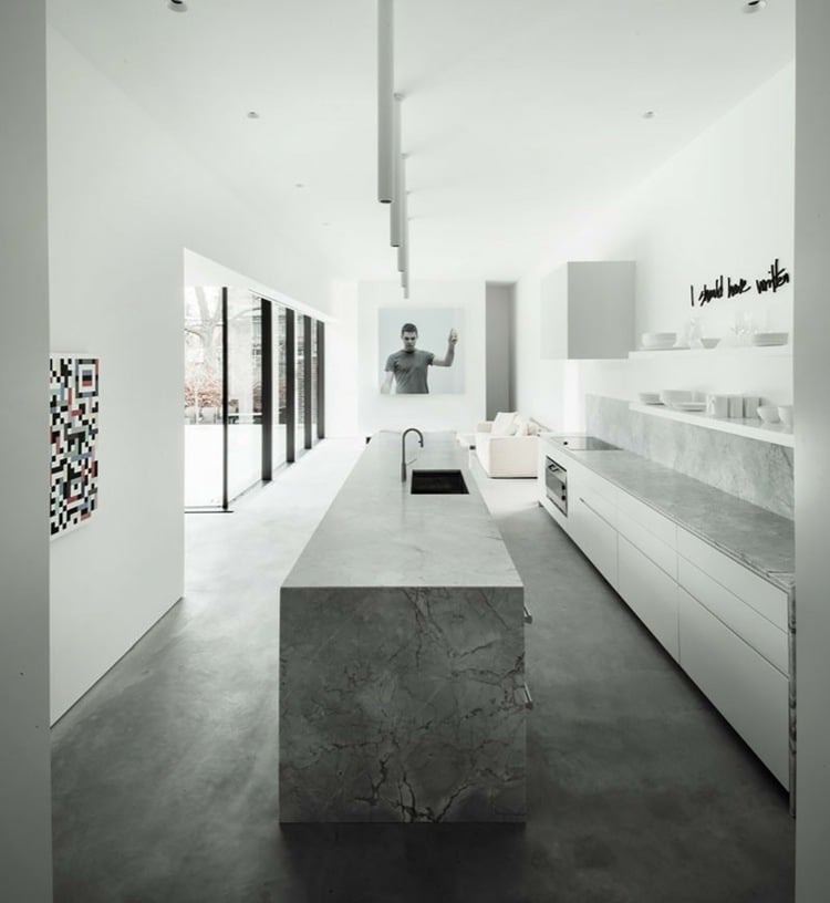 Grauer Naturstein und Sichtbeton als Fußboden für ein monochromes Design im weißen Küchendesign