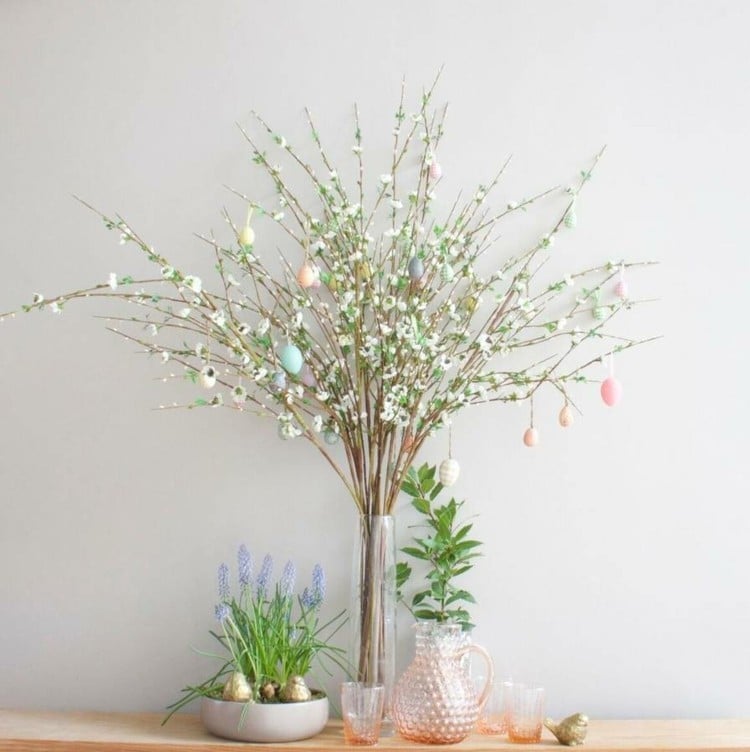 Modernes Arrangement für den Osterstrauch aus weißen Blüten in einer schmalen Glasvase