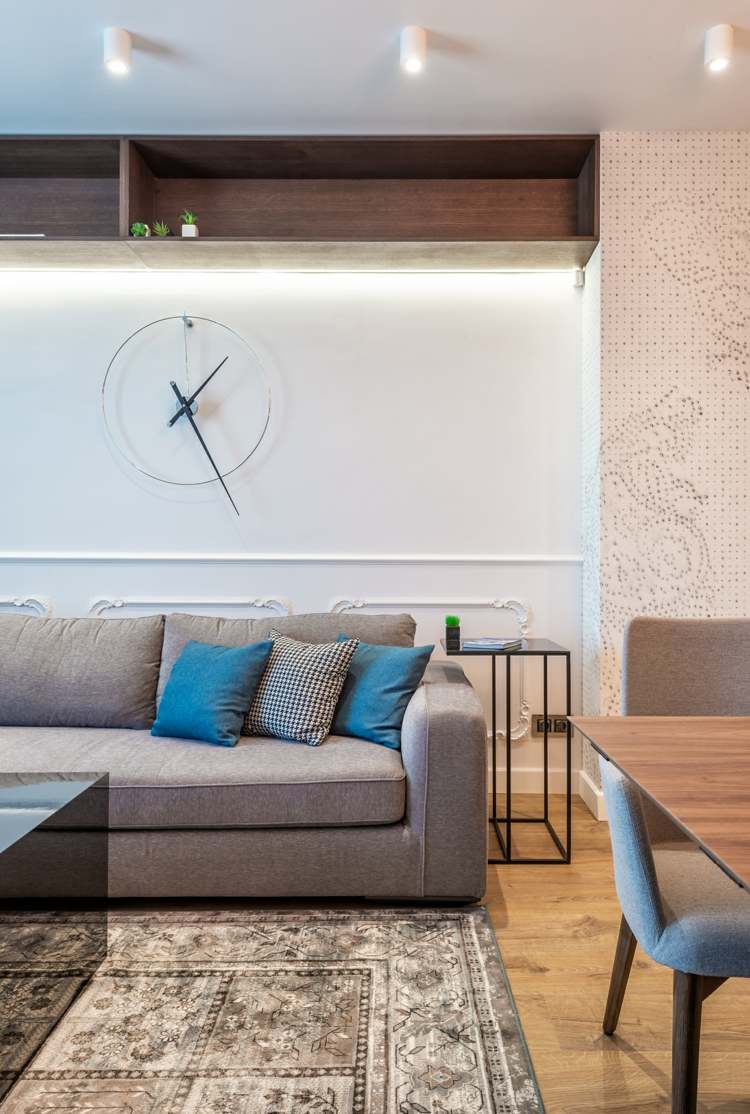 Wohnzimmer in modernem und zeitlosem Stil mit grauem Sofa und origineller Uhr als Wanddeko