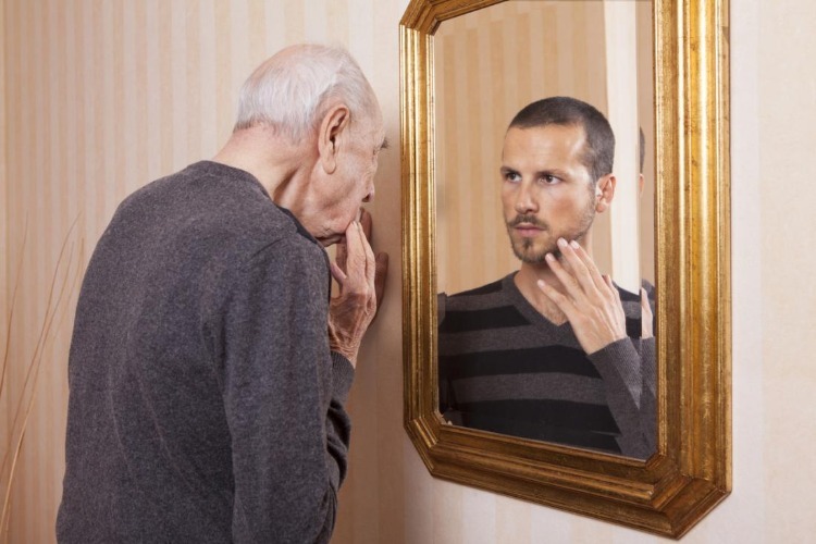 alter mann sieht sich als jung im spiegel an
