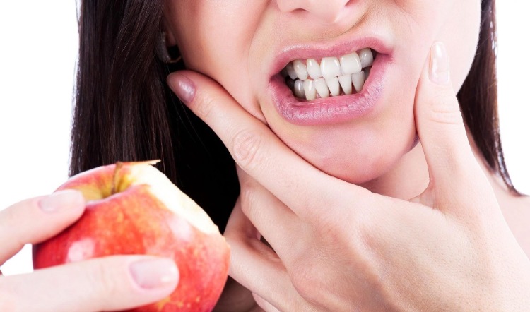 empfindliche zähne hausmittel zahnempfindlichkeit behandeln frau mit apfel